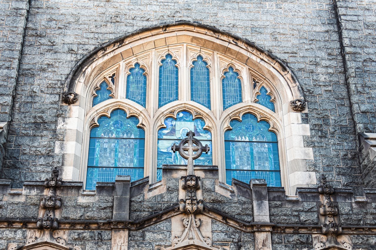 Beautiful gothic church window with intricate stained glass and cross in architectural design.
